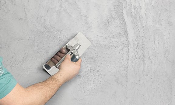 Mann spachtelt die Wand