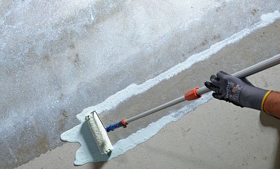 Person verteilt Klebstoff auf dem Boden