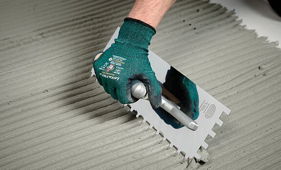 Mann verteilt Mörtel auf Untergrund